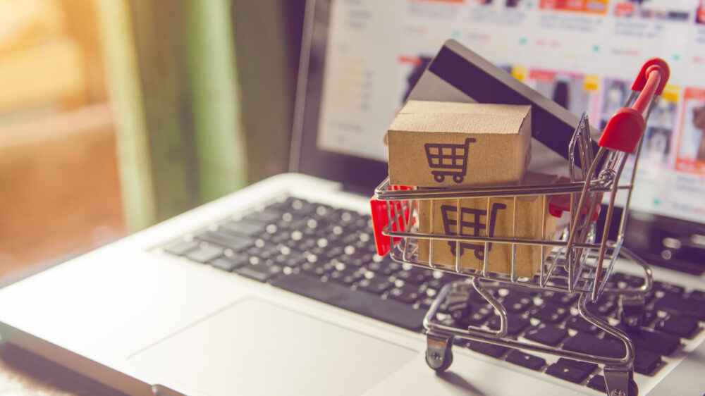 Shopping online concept - Parcel or Paper cartons with a shopping cart logo in a trolley on a laptop keyboard. Shopping service on The online web. with payment by credit card and offers home delivery.